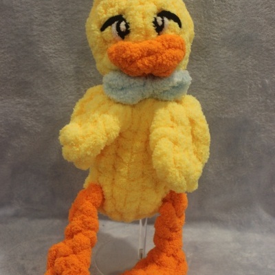 Peluche de pato amarelo com bico e pés laranja e laço azul claro