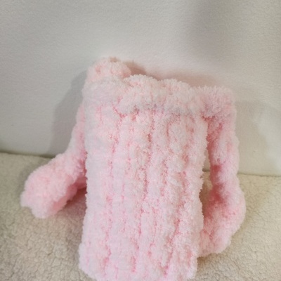 Toalha ou capa felpuda cor-de-rosa clara sobre superfície creme e parede branca.