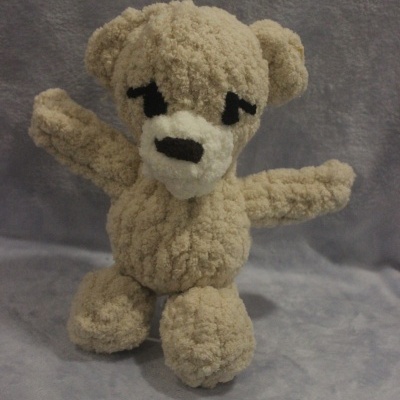 Ursinho de peluche bege com focinho branco e olhos e nariz pretos