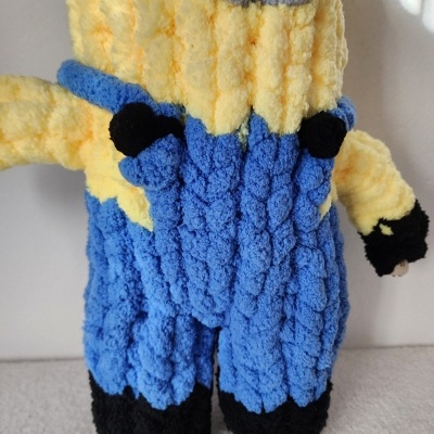 Boneco felpudo em amarelo, azul, preto, cinzento e branco com textura ondulada