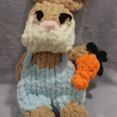 Boneco de coelho de peluche castanho com roupa azul e cenoura laranja