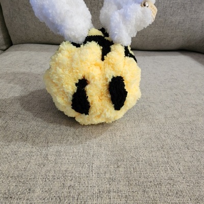 Brinquedo de pompons a parecer uma abelha em sofá cinza