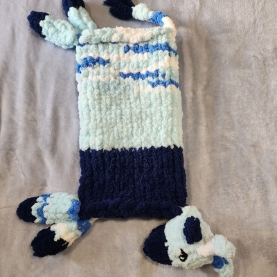 Cobertor ou manta de bebé tricotada com padrão azul e branco e cabeça de animal no canto