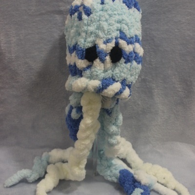 Boneco de pelúcia azul e branco em forma de polvo com tentáculos e olhos pretos