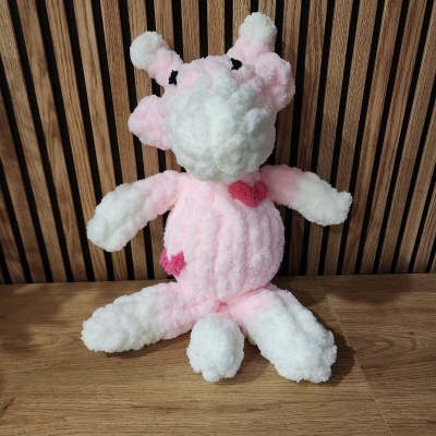 Peluche rosa e branco com corações cor-de-rosa sentado em madeira.