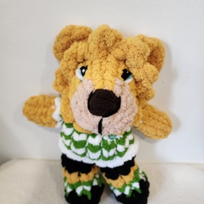 Boneco de peluche leão colorido com roupa contra parede branca
