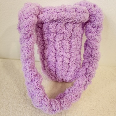 Bolsa tipo saco felpudo lilás com textura acolchoada.