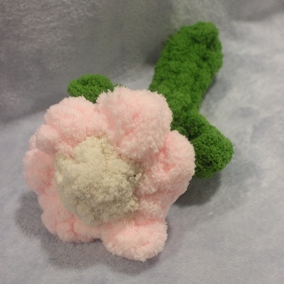 Flor de pompons de lã cor-de-rosa, creme e verde em fundo cinza