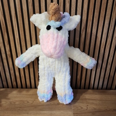 Pelúcia de unicórnio colorido sobre superfície de madeira