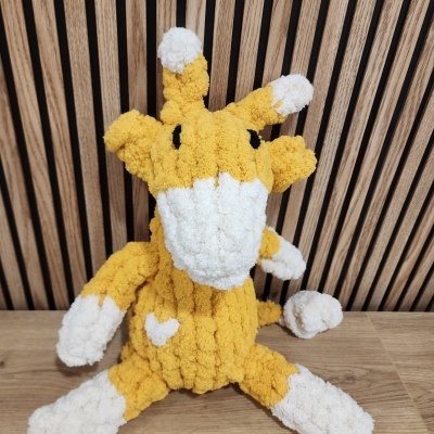 Pelúcia de girafa amarelo e branco com textura felpuda sentada na madeira