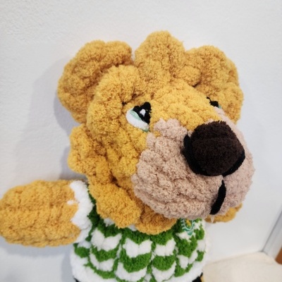 Urso de peluche amarelo com roupa verde, branco e preto