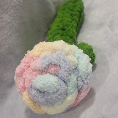 Brinquedo de pelúcia colorido em forma de flor sobre tecido cinza