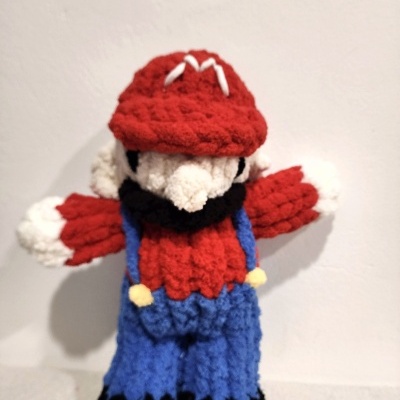 Boneco de crochet com boné vermelho e roupa colorida