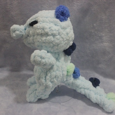 Pelúcia artesanal azul claro e escuro com pontos verdes sobre fundo cinza