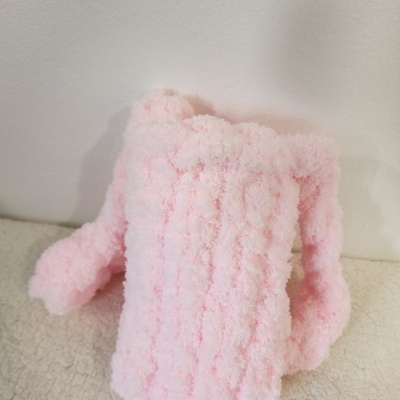 Mochila rosa claro felpuda com alças sobre superfície creme