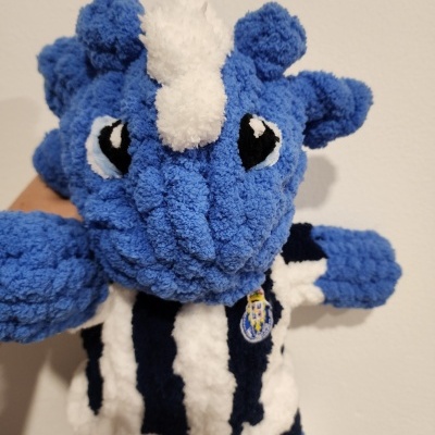 Boneco de pelúcia azul com camisola às riscas e emblema