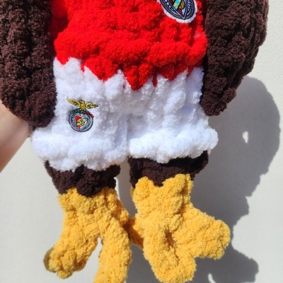 Boneco de pelúcia colorido com textura felpuda e emblemas bordados.
