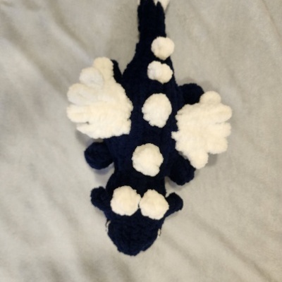 Boneco de pelúcia azul escuro com manchas e detalhes brancos