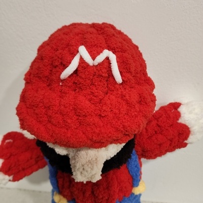 Boneco de peluche com gorro vermelho e letra branca M bordada