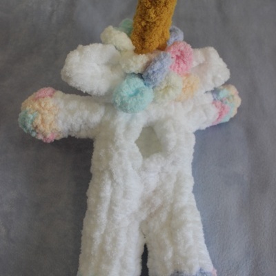 Boneco de pelúcia unicórnio branco com chifre amarelo e detalhes coloridos suaves