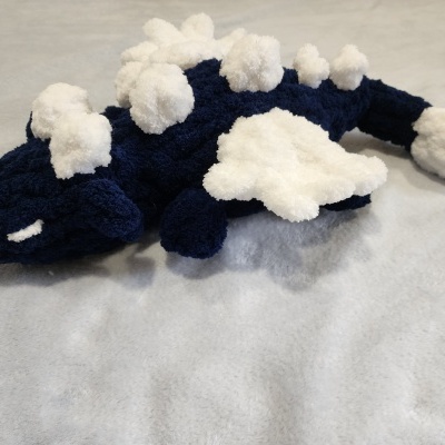 Pelúcia de dinossauro azul escuro com manchas brancas, texturas felpudas