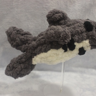 Pelúcia felpuda em forma de orca cinzenta e branca sobre suporte transparente