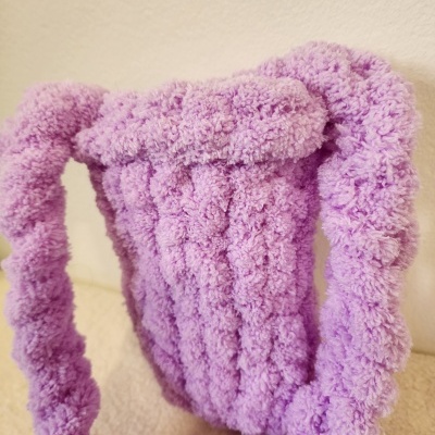 Mala de mão lavanda felpuda com alças em fundo neutro.