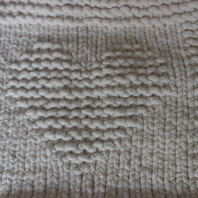 Tapete de tecido chenille creme com padrão em relevo, visto de perto