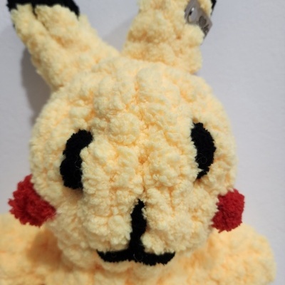 Boneco de peluche amarelo felpudo com orelhas pretas e bochechas vermelhas