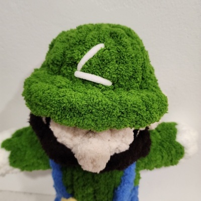 Boneco em tecido felpudo com chapéu verde e detalhe branco