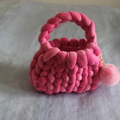 Mala de mão rosa trançada com bola felpuda pendurada