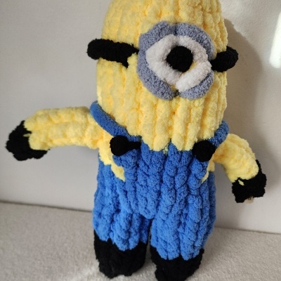 Boneco de croché amarelo e azul com um olho grande