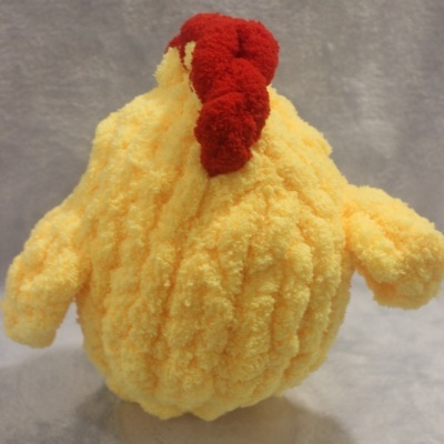Boneco de peluche amarelo em forma de galinha com crista vermelha