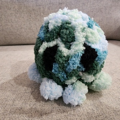 Pelúcia colorida de pompons numa superfície de sofá cinzento