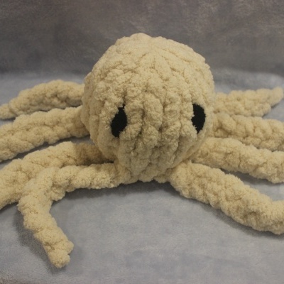 Pelúcia de polvo bege com olhos pretos e etiqueta HAND MADE sobre superfície cinza