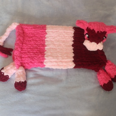 Almofada em forma de carneiro rosa feita de tecido peludo sobre fundo cinza