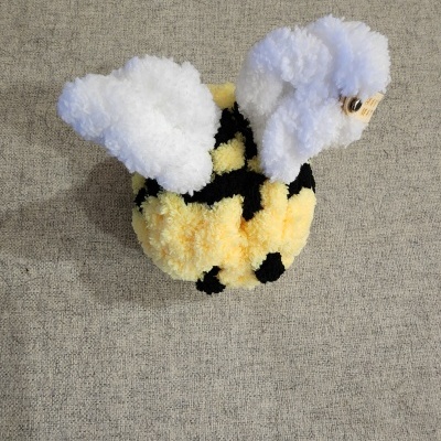 Boneco artesanal de pompons com formato de abelha em amarelo, preto e branco
