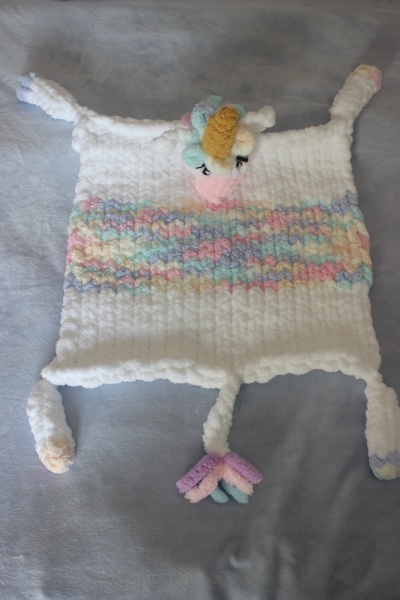 Manta ou cobertor em crochet branca com faixas pastel e unicórnio em relevo.