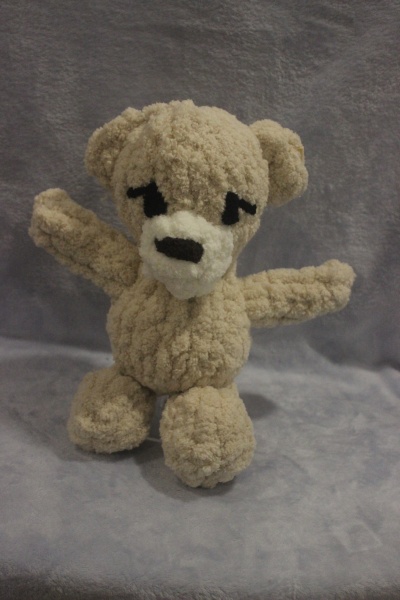 Ursinho de peluche bege com focinho branco e olhos e nariz pretos