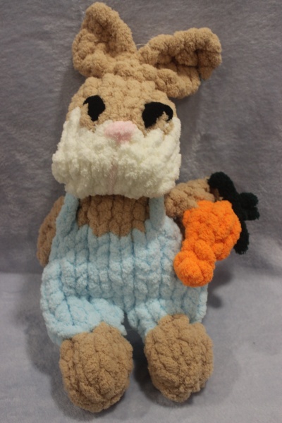 Boneco de coelho de peluche castanho com roupa azul e cenoura laranja