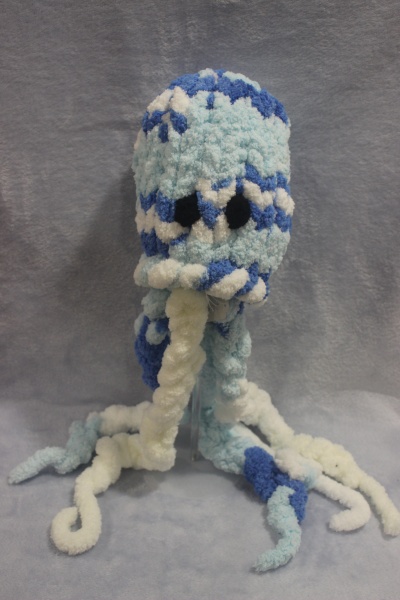 Boneco de pelúcia azul e branco em forma de polvo com tentáculos e olhos pretos