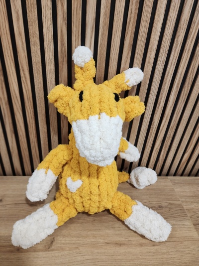 Pelúcia de girafa amarelo e branco com textura felpuda sentada na madeira