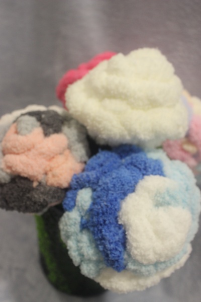 Arranjo colorido de flores feitas de pompons de lã