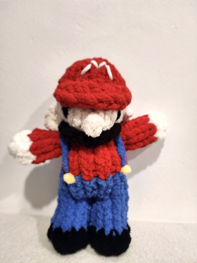 Boneco de crochet com boné vermelho e roupa colorida