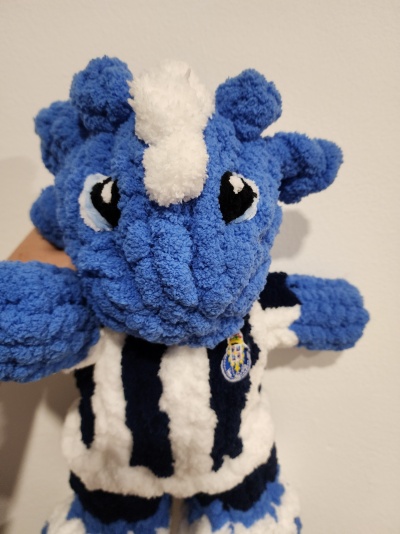 Boneco de pelúcia azul com camisola às riscas e emblema
