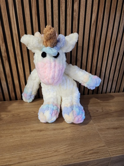 Pelúcia de unicórnio colorida em tons pastel sobre superfície de madeira