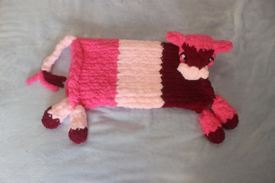 Almofada em forma de carneiro rosa feita de tecido peludo sobre fundo cinza