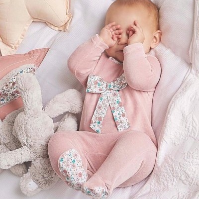 bebé com fato rosa e laço com detalhes florais e brinquedo de peluche coelho