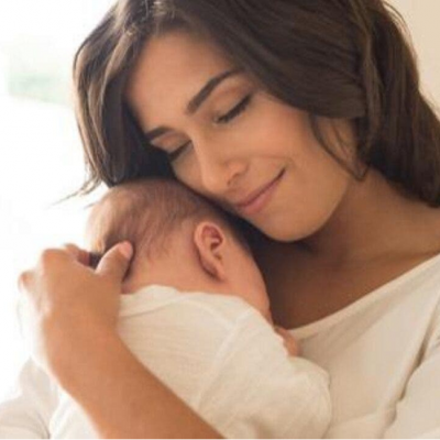 Mulher segurando bebé vestido de branco em ambiente interior