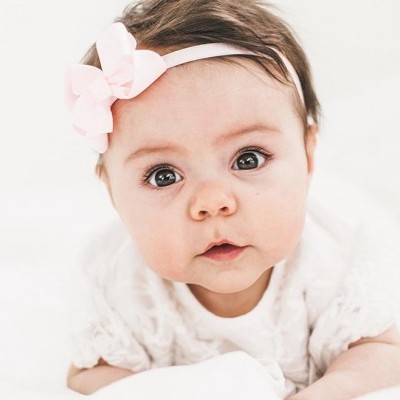 Bebé com blusa branca e fita de cabelo cor-de-rosa